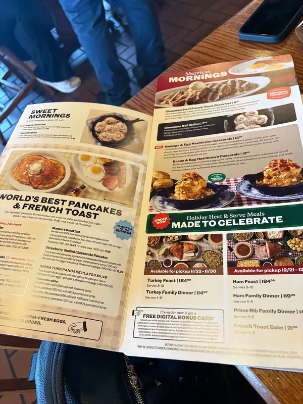 Open menu spread across two pages, one headed Sweet Mornings and World's Best Pancakes & French Toast, the other Merriest Mornings with a green Holiday Heat & Serve Meals block.