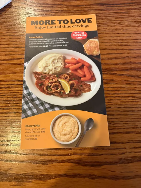Tabletop card headed More To Love on an orange and dark brown ground, showing a Creole catfish plate and a bowl of cheesy grits.