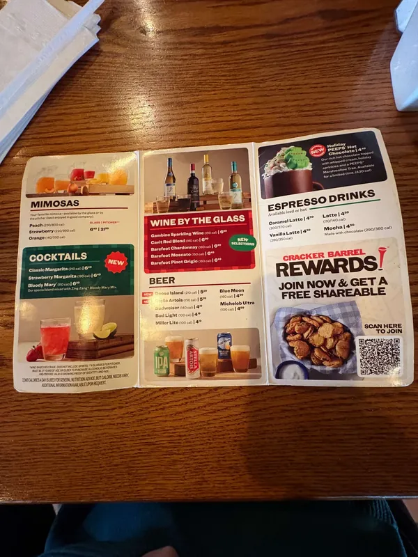 Trifold drinks menu open on a table, with Mimosas and Cocktails, Wine by the Glass and Beer, and a Cracker Barrel Rewards panel with a QR code.