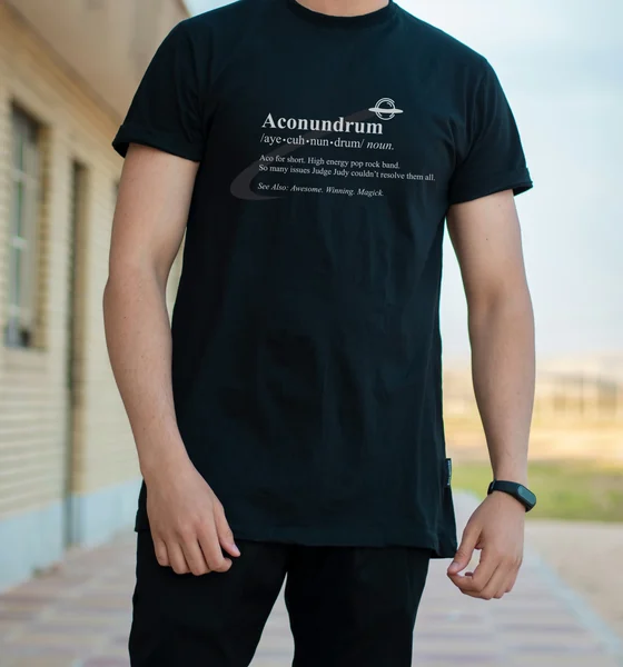 Person wearing a black Aconundrum t-shirt printed with the band name, a dictionary-style definition, and a small flying saucer.