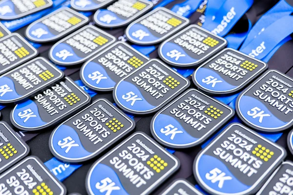 A pile of finisher medals shaped like the Sports Summit badge, each reading 5K in blue and yellow.